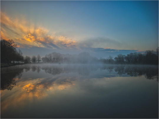 Levé de soleil hivernal et légère brume sur un étang.